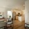 Spacious and well lit living room with wood flooring, large windows and open access to the kitchen