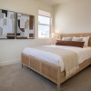 Large well lit bedroom with carpeted floors and a large window 